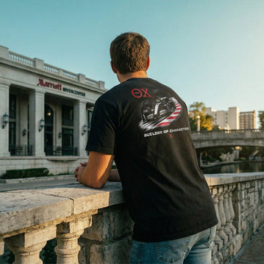 Back view of a model wearing the black Theta Chi F1 tee outdoors, showcasing the full Formula racing graphic design.