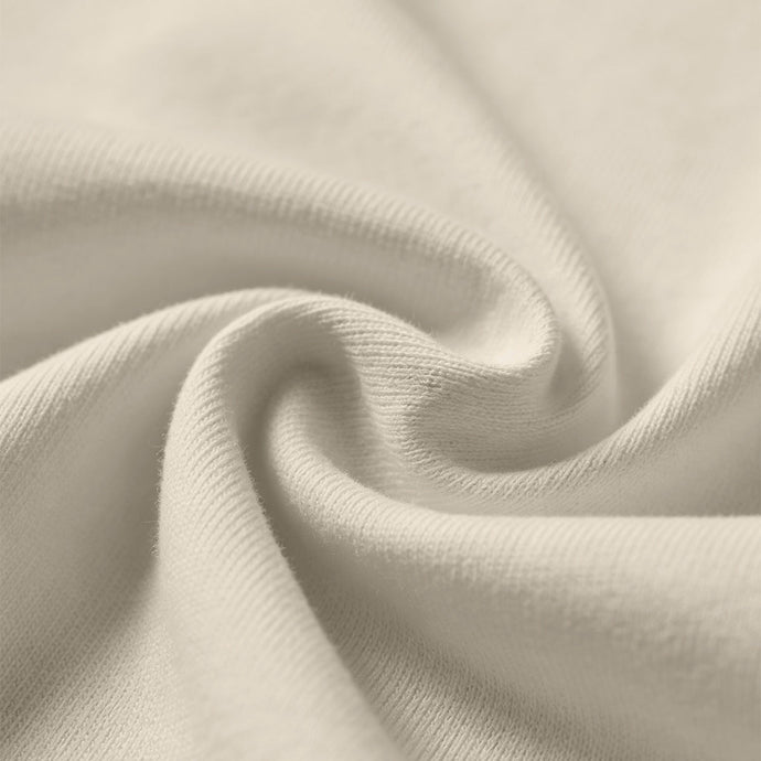Soft beige fabric close-up showing a smooth, heavyweight knit texture with gentle folds and subtle draping.